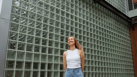 clip-4013924085-standing-front-glass-brick-wall-young-woman