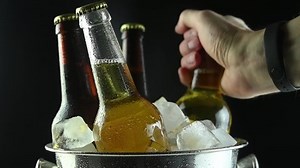 male hand takes a bottle of beer from a bucket