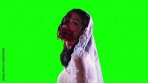 Creepy female zombie looking at the camera with wounded face and wearing bride gown. Shot in 4k resolution with green screen background