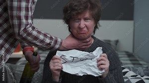 Alcoholic man strangles woman with facial and dental injuries by neck, she cries and asks for help, unrolling paper with inscription STOP. Topic acogolism and domestic violence. Abuse women concept.