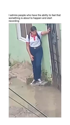 Daily Joy USA 🇺🇸 on Instagram: "In a flooded urban alley under overcast skies a determined student in crisp white uniform and backpack reaches their green house gate blocked by deep muddy water. With hilarious resolve they contort into acrobatic poses leaning against the wall bending backwards and stretching impossibly to unlock the gate without getting wet. Each twist and slow-motion slide builds comedic tension knees buckling as they battle the deluge. Finally the gate swings open for a triu