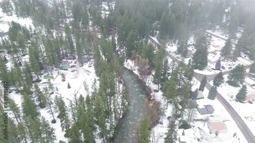 Creekside residences line the Peshastin Creek channel near local connector roads north of RV Park. Snow packed roofs, flowing dark water, dense conifers create layered contrast in Peshastin, WA