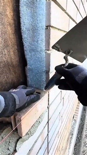 Applying mortar between brick joints and smoothing edges while building exterior wall