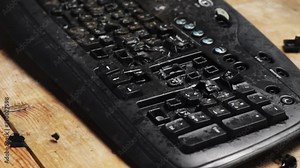 A fired worker smashes a computer keyboard with a hammer. Shattered desktop keyboard. Broken office equipment. The losing computer player breaks the keyboard. Depression at work.