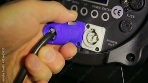 The hand of the illuminator worker connects the mains electrical wire to the profile projector Stock Video