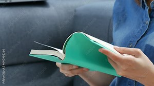 Young asian woman reading book on cozy couch sofa at warm home. Relax woman holding book read on sofa near window happiness.woman reading open book leisure mind. Happiness woman lifestyle at home