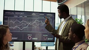 Coworkers engaging in a problem solving meeting at a corporation, using an interactive board to visualize data and develop solutions for complex challenges. Analysis presentation. Camera B.