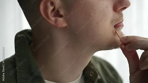 A man uses a toothpick. A man with a toothpick in his teeth. The food is stuck in the teeth and the man takes the food out of his teeth. Dental floss. Dental care.