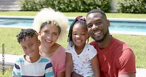 African American family with a young biracial woman smiles together outdoors at home