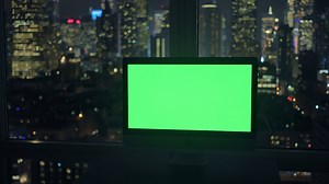 Computer screen isolated with green screen background in city office at night