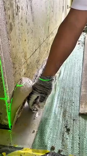 Worker applying cement plaster guided by green laser line