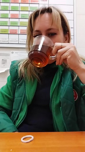 Person in Green Jacket Enjoys Tea at a Wooden Table