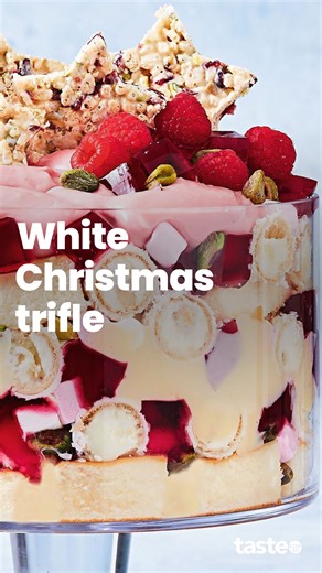 Inspired by white Christmas, this pretty-in-pink trifle is filled with sponge, jelly, custard, Raffaello chocolates, raspberries and topped off with Christmas stars! For the recipe, Google 'Taste white Christmas trifle'. Recipe by @foodie.lucy22 #trifle #triflerecipe #triflerecipes | Taste.com.au
