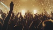 Crowd dancing and cheering at a concert while glitter is falling from...