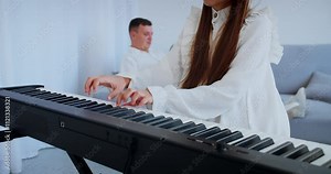 Child musician plays digital piano with father on background. Girl hands press keys, Improving skills of playing musical instrument