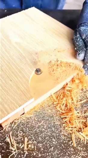 Gloved hand guides wood along router—bit carves smooth edge as sawdust swirls in rhythmic shaping.
