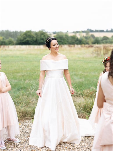 Real bride wearing custom Kate Edmondson bridal gown. We created two bespoke dresses for our bride. Off the shoulder princess line dress in a pastel pink. For her outdoor wedding in the Hertfordshire countryside. #luxurybride #bespokedesign #weddingdress #couturefashion #bridaldesigner