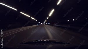 Fast car ride through city at night in rays of street lights, long exposure. Reflection of rays neon signs and lights, in windshield of auto. Theme a quick moved automobile on town and nightlife.