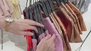Women's clothing store, woman browsing clothes racks. Young female shopper trying on new clothes in mall. Women's clothing. Wardrobe. Sale, shopping, fashion, style
