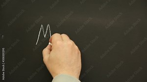 Writing the words 'Music' on a Chalkboard - The person is using chalk to write with their hand this text. Stock Video Clip Footage