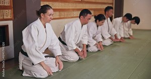 Dojo, people and respect with bow for karate, martial arts practice or greeting with honor in class. Group, students and etiquette with kneeling for learning combat, self defense or training in Japan