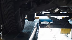 Vehicle hoisted on a pneumatic lift in a workshop for maintenance.