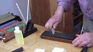This video is the second in the Knife Sharpening Video Series. It explains the process of using sharpening stones to sharpen a knife, gives a bit of history relating to sharpening stones and explains the differences between some of the materials used to make sharpening stones. It features Hard Arkansas stone as an example, but gives information on a variety of different stones. It also teaches users how to clean, care for, and store natural stones. | A.G. Russell Knives