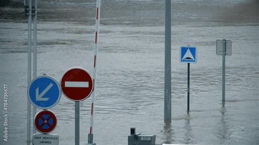 Flooded road with road signs, River Seine in Paris, France. Text in French: except lafarge vehicles