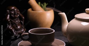 Tea ceremony on a shepherd with Buddha figures close-up. Conducting a traditional tea ceremony with Chinese ( English ) tea. Concept of: Lemon, Steam, Hot, Warm, Cold.