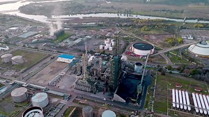 Premium stock video - Aerial orbit of an oil refinery and its fractionation tower with the tanks in the background, natural environment