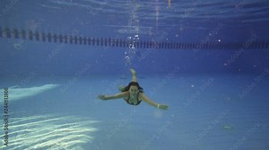 Young girl swims under water in swimming pool. Slow motion.