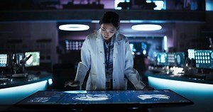 現代のバイオテクノロジー研究センターでディスプレイ上のMRIとインタラクティブタッチスクリーンテーブルを使用してアジアの神経科学者の女性。脳損傷患者のために革新的なデバイスを開発している医師。