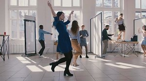 Two young fun female business partners dancing together celebrating victory with multiethnic company staff slow motion.