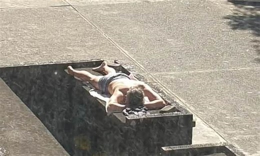Bizarre moment locked down man soaks up the sun on top of a BIN room