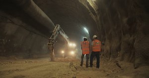 Construction workers supervising heavy machinery during tunnel construction work
