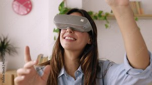 Excited young woman wearing virtual reality googles at studio office. Businesswoman with VR goggles headset living a metaverse experience. Virtual reality and metaverse gaming concept