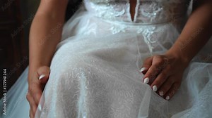 The girl touches her beautiful white dress with her hands. Everything is shot in close-up