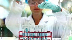 Pretty science student using pipette to fill test tubes