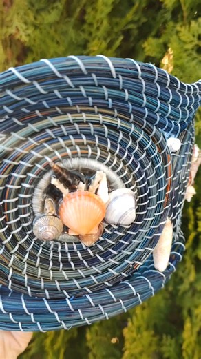 #516, $275.00 This ocean-themed basket is about 10½" diam x 6" deep. It took at least 28 hrs to build the basket, not including the needle prep (harvesting, glycerin treatment, dying). It features sea glass on the inside of each panel and seashells on the outside. A small sand dollar centers the base of the basket. I'll be taking this to Camden Art Shoppes Friday for display and sale. #ocean #oceanwaves #seashells #baskets #pineneedlebasketry | Janice Phillips Basketry