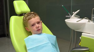 Kid crying in dental chair. Sad Caucasian child boy came to see the dentist