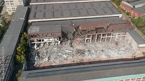 Aerial footage with demolition machinery working on dismantling old industrial manufacturing buildings, clearing land for new projects under development. Stock Video