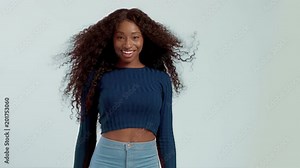 woman with long curly hair dancing and shaking hair and smiling. Have fun shaking head