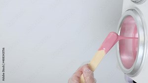 Process of depilatory wax heated and melted in a special device. Beauty master mixes the heating wax with a wooden spatula before the depilation waxing procedure. Vertical video
