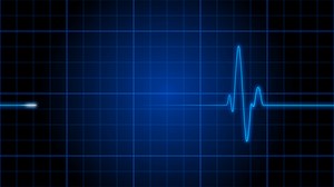 Download An electrocardiogram heart monitor pulses on a blue grid - Loop for free