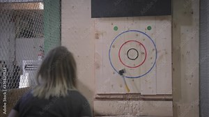Slow motion footage of a girl throwing an axe at a target.