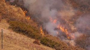 Flames from fire burning out of control through brush on mountainside in Utah during a dry Fall season.