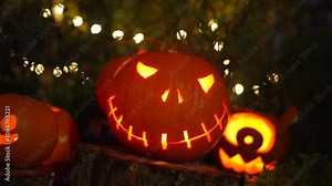 A scary glowing carved pumpkin flickers with candlelight on Halloween night, fairy lights in the background, creating a haunting, spooky atmosphere in slow motion