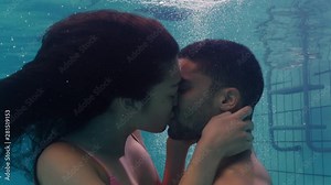 young couple kissing underwater in swimming pool enjoying intimate kiss romantic lovers submerged in water floating with bubbles in passionate intimacy