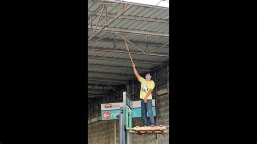 Worker stands on forklift to reach and catch python at warehouse