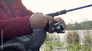 Close up angler senior adult mature fisherman standing near river with fishing rod, reel hand rotation, casts his line into water, nature embrace overcast skies. Hobby, adventure, leisure relaxation